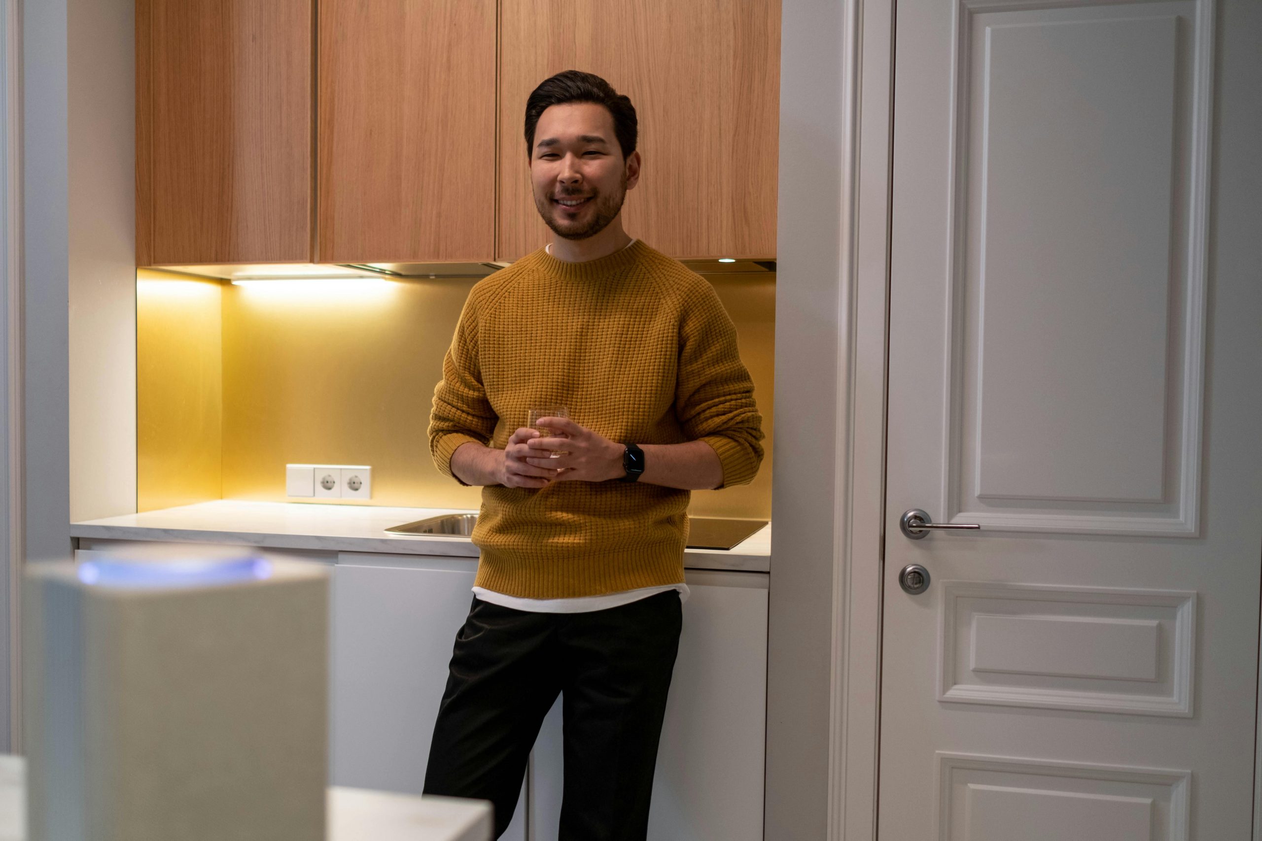 man standing in a modern kitchen with cabinets behind him