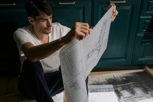 man reviewing a remodel plan while seated behind kitchen cabinets
