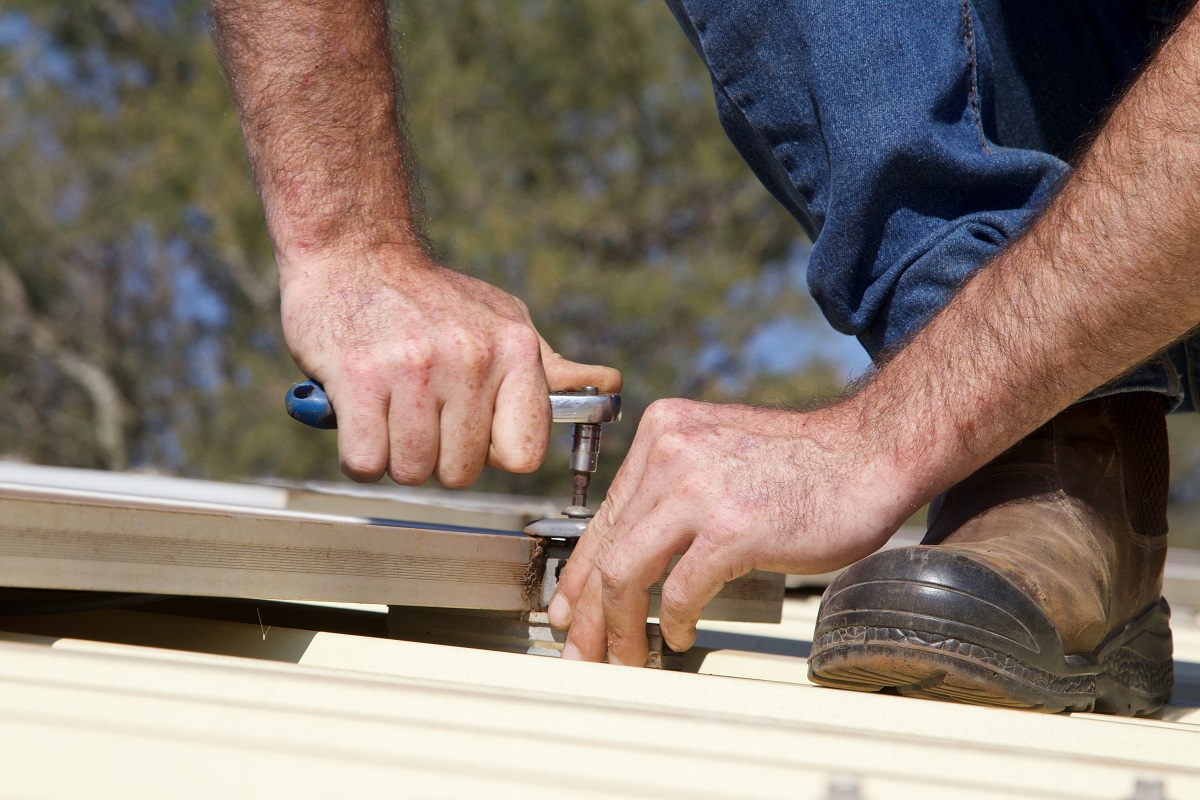 close-up of a man fastening metal roofing